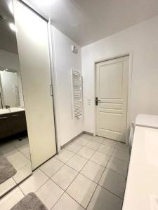 a white bathroom with a door and a mirror at Superbe chambre avec terrasse (clim optionnel) in Bagneux