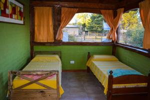 two beds in a green room with a window at cabaña 1 santa catalina in Villa Giardino