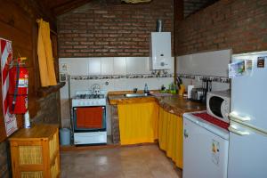 a kitchen with yellow cabinets and a white refrigerator at cabaña 1 santa catalina in Villa Giardino