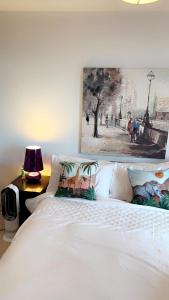 um quarto com uma cama branca e uma pintura na parede em ComfyCozy Luxury Apartment Canning Town em Londres