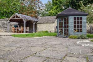 a stone patio with a gazebo and a house at Holly Cottage, Coln St Aldwyns, Cotswolds in Cirencester