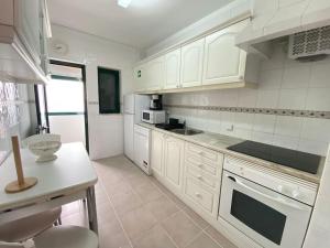 - une cuisine avec des armoires et des appareils blancs dans l'établissement Apartamento Amparo-T2 c/piscina, à Carvoeiro