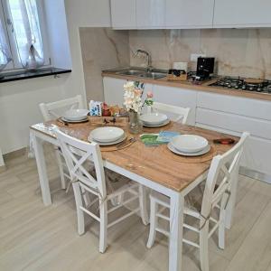 uma mesa de madeira com cadeiras brancas e uma cozinha em Casa Vacanze Argento em Bacoli