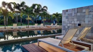 - un groupe de chaises assises sur une terrasse en bois à côté d'une piscine dans l'établissement île de Pipa - Ma Plage Hotel, à Pipa