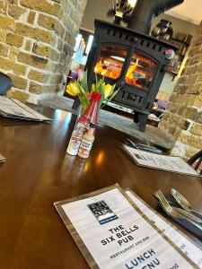 a table with flowers in a bottle and a fireplace at The Six Bells in Rochester