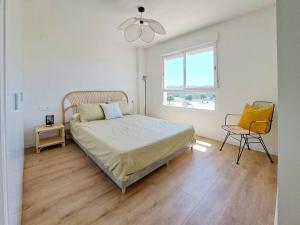 a bedroom with a bed and a chair and a window at Charming flat close to the beach in Canet de Berenguer