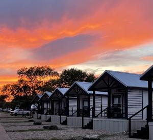 una fila de casas con una puesta de sol en el fondo en HTR TX Hill Country Campground, en Kerrville