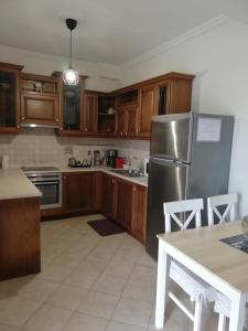uma cozinha com armários de madeira e um frigorífico de aço inoxidável em Sunny stay furnished apartment in Kanoni em Kanoni