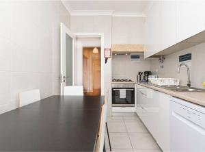 cocina con armarios blancos y encimera negra en HOUZE_4 room flat in Central Lisbon near Zoo, en Lisboa