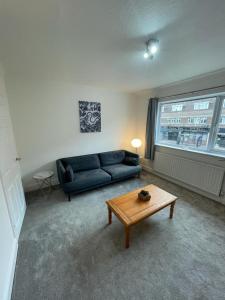a living room with a blue couch and a coffee table at 4 Bedroom Flat In Watford in Leavesden Green