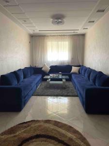 a living room with a blue couch and a table at Logement entier : appartement in Larache