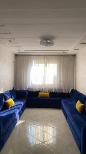 a living room with a blue couch and yellow pillows at Logement entier : appartement in Larache