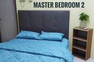 a bed with a blue comforter and a night stand at Krystal Homestay in Kulim