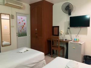 a room with two beds and a desk and a television at MD House in Chiang Mai