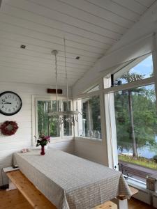 une chambre avec une table, une horloge et des fenêtres dans l'établissement Villa Valkeinen, à Nilsiä