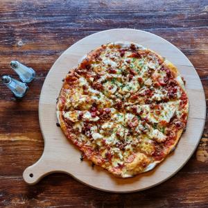 a pizza on a wooden cutting board on a table at The Queen Vic Hotel in Monkwearmouth