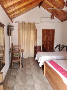 a room with two beds and a table and a desk at Home Stay Resort in Nilaveli