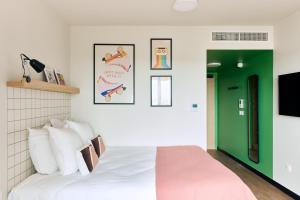 a bedroom with a white bed and a green door at Hife Toulouse Labège in Labège