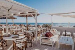 een patio met witte tafels en stoelen en het strand bij Appartement à 5 min de la plage in Aroeira