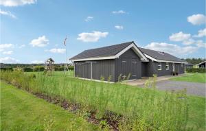 ein schwarzes Gebäude mit einem Grasfeld davor in der Unterkunft 4 Bedroom Cozy Home In Hadsund in Hadsund