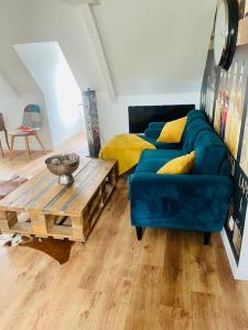 sala de estar con sofá azul y mesa de madera en L idylle de Guillaume, en Falaise