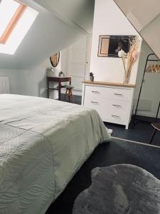 een slaapkamer met een bed en een dressoir met een spiegel bij L idylle de Guillaume in Falaise