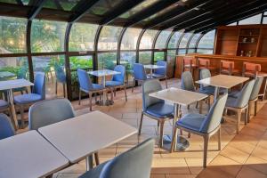 ein Restaurant mit Tischen, Stühlen und Fenstern in der Unterkunft All Seasons Resort, Trademark Collection by Wyndham in South Yarmouth