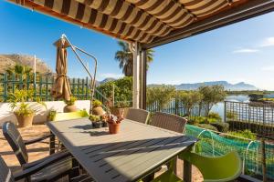 un patio con mesa y sillas y vistas al agua en Vlei Cove en Ciudad del Cabo