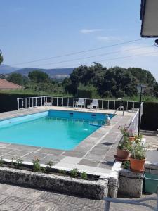 uma grande piscina azul com cadeiras e plantas em Chalet en la sierra de Guadarrama em Alpedrete