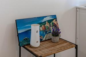 a vase sitting on a table next to a painting at H11 [Bussana 1A] Mare in Bussana Nuova