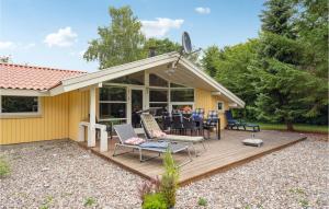 SkattebølleにあるNice Home In Tranekr With 3 Bedrooms, Sauna And Wifiの木製デッキ(テーブル、椅子付)が備わる家