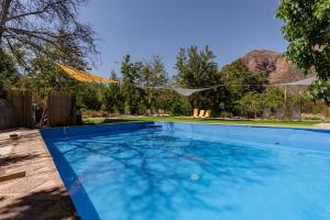 a swimming pool with blue water in a yard at Cabaña Jacuzzi Exterior Privado in San José de Maipo
