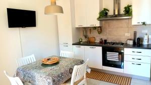 a kitchen with a table with white chairs and a television at - CASA MANZONI - Luminoso appartamento zona Sferisterio in Macerata