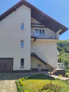 ein weißes Haus mit einem Balkon und einem Hof in der Unterkunft Smeštaj Milekić - Nova Varoš in Vraneša