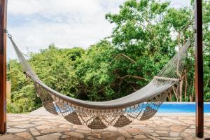 a hammock in a resort with trees in the background at Exquisite Private Coastal Retreat home in San Juan del Sur