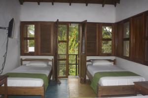 two beds are in a room with windows at Waira Selva Hotel in Puerto Nariño