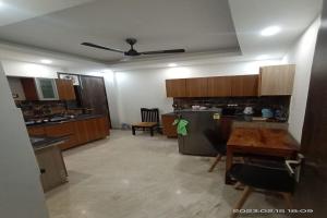 a large kitchen with wooden cabinets and a table at Mintstar Apartment and Suites, East of Kailash in New Delhi