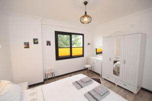 a white bedroom with two beds and a desk at Villa Manzara in Selçuk