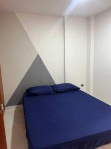 Cama azul en una habitación con pared en Apartamento bien ubicado. en Bucaramanga