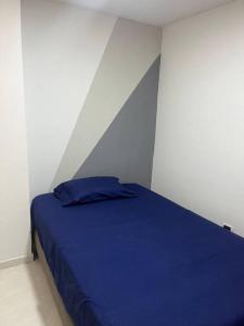 Apartamento bien ubicado. في بوكارامانغا: غرفة نوم بسرير ازرق في غرفة بيضاء