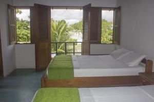 a bedroom with two beds and a balcony with windows at Waira Selva Hotel in Puerto Nariño
