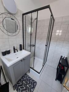 ein Bad mit einer Dusche, einem Waschbecken und einem Spiegel in der Unterkunft Margit Ház in Nemesbükk