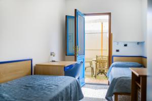a bedroom with two beds and a desk and a door at La Capannina in Procida