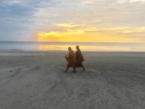 two people walking on the beach at sunset at Nichahome By Kannika in Hua Hin