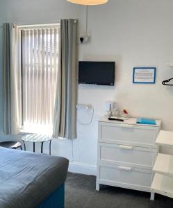 a bedroom with a bed and a dresser and a television at The Hotel Blackpool in Blackpool