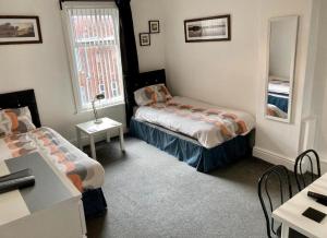 a room with two beds and a table and a mirror at The Hotel Blackpool in Blackpool