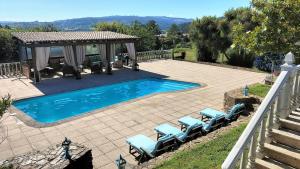 a swimming pool with chairs and a gazebo at As Seis Chemineas in San Xulián de Sales