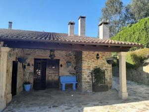 a stone house with a blue bench in front of it at As Seis Chemineas in San Xulián de Sales