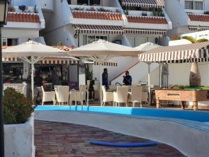 a swimming pool with umbrellas and tables and chairs at NEWQUAY in Playa de las Americas