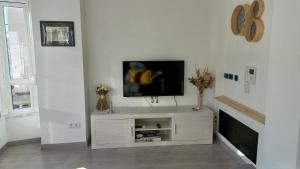 sala de estar con TV de pantalla plana en una pared blanca en Lar ABEANCOS en Melide